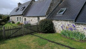 Een stenen huis met een schuin dak en een houten omheining.