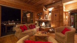 A cozy log cabin interior with a fireplace, wooden furniture, and a dining area.
