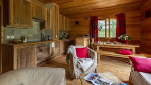A cozy cabin-style kitchen with wooden cabinets, a dining area with a bench, and a covered chair.