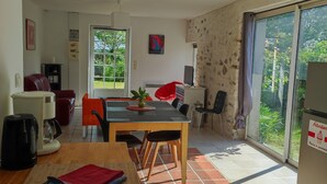 Un salón espacioso con una mesa de comedor de madera, un sofá rojo y un amplio ventanal con vistas a zonas verdes.