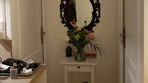 A room with a white door, a black ornate mirror, and a shelf with a vase of flowers. - In the heart of the city center (Blois)