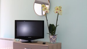 A television on a wooden dresser with drawers, a mirror above it, and two potted orchids on the dresser. - Magnificent sea view in front of the beach at Trez de Bénodet (Bénodet)