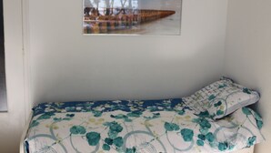 A single bed with a floral bedspread, a framed picture on the wall, and a window to the left. - Magnificent sea view in front of the beach at Trez de Bénodet (Bénodet)