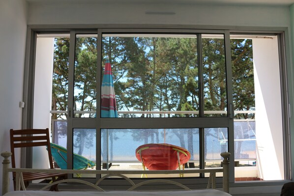 Una habitación con un ventanal grande, una cama, una silla de madera y una silla roja.