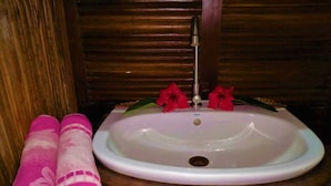 Een badkamer met een witte wasbak, twee roze handdoeken en een houten wastafelmeubel.