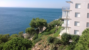 Un edificio costero con balcón que da al mar, rodeado de vegetación.