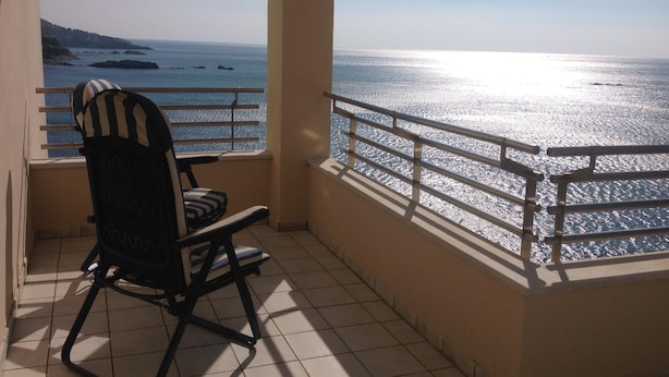 Un balcón con vista al mar, una silla y una barandilla.