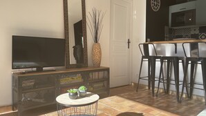 A living room with a TV, a decorative mirror, a vase with plants, and a small round table. - MAZET DE LOLA little Provencal house (Saint-Rémy-de-Provence)