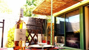 A table set outdoors with a bottle of wine, glasses, and a chair. - MAZET DE LOLA little Provencal house (Saint-Rémy-de-Provence)