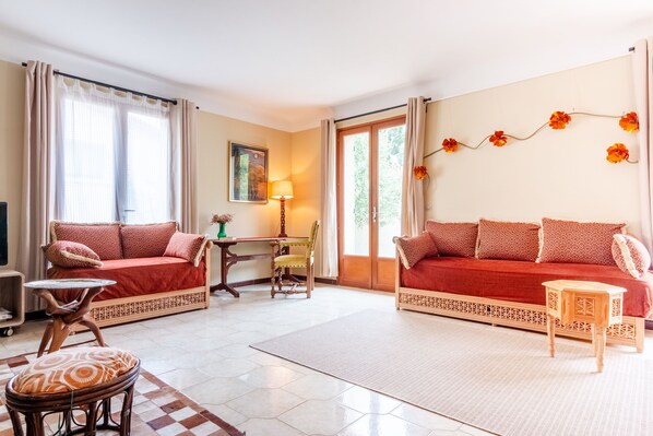 A living room with a red sofa, a wooden chair, a small table, and a lamp. - House with views, haven of peace, 2 steps from the center of Céret. 4 to 6Pers (Céret)