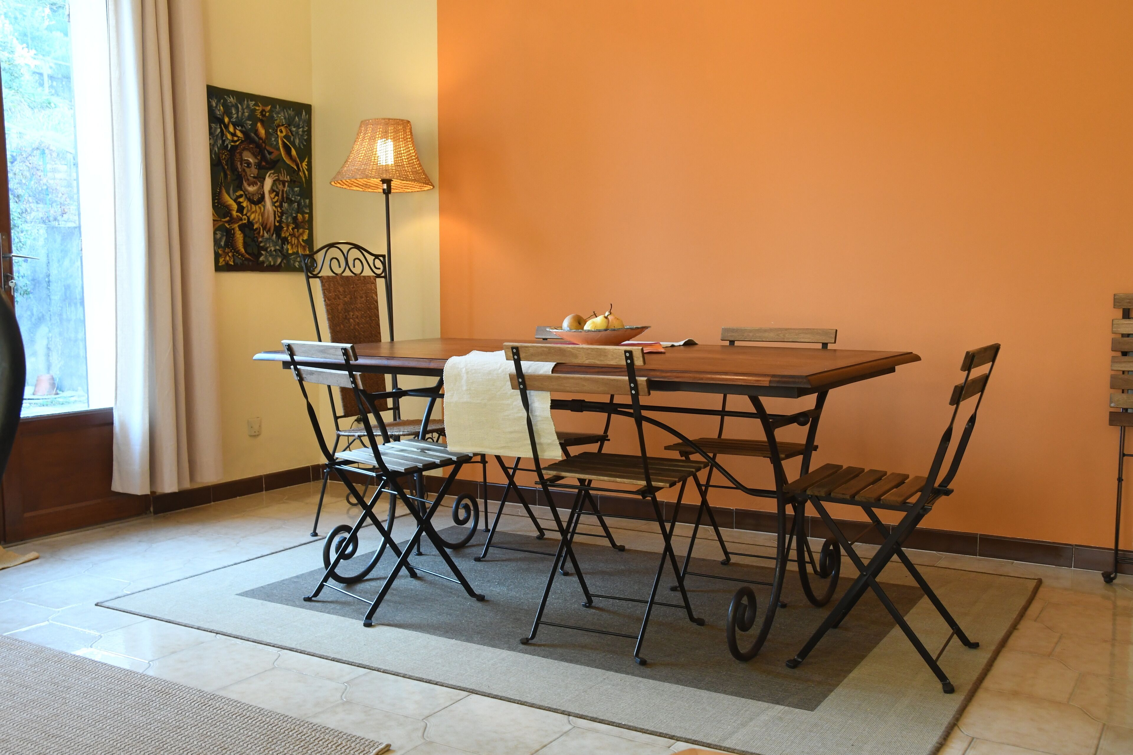Un comedor con una mesa, sillas, una lámpara y un cuadro en la pared.