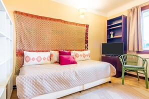 A neatly arranged bedroom with a bed, a television, a chair, and a shelf with a vase. - House with views, haven of peace, 2 steps from the center of Céret. 4 to 6Pers (Céret)