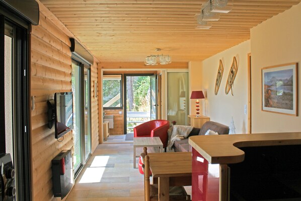 A wooden interior with a sofa, a table, and a red chair.