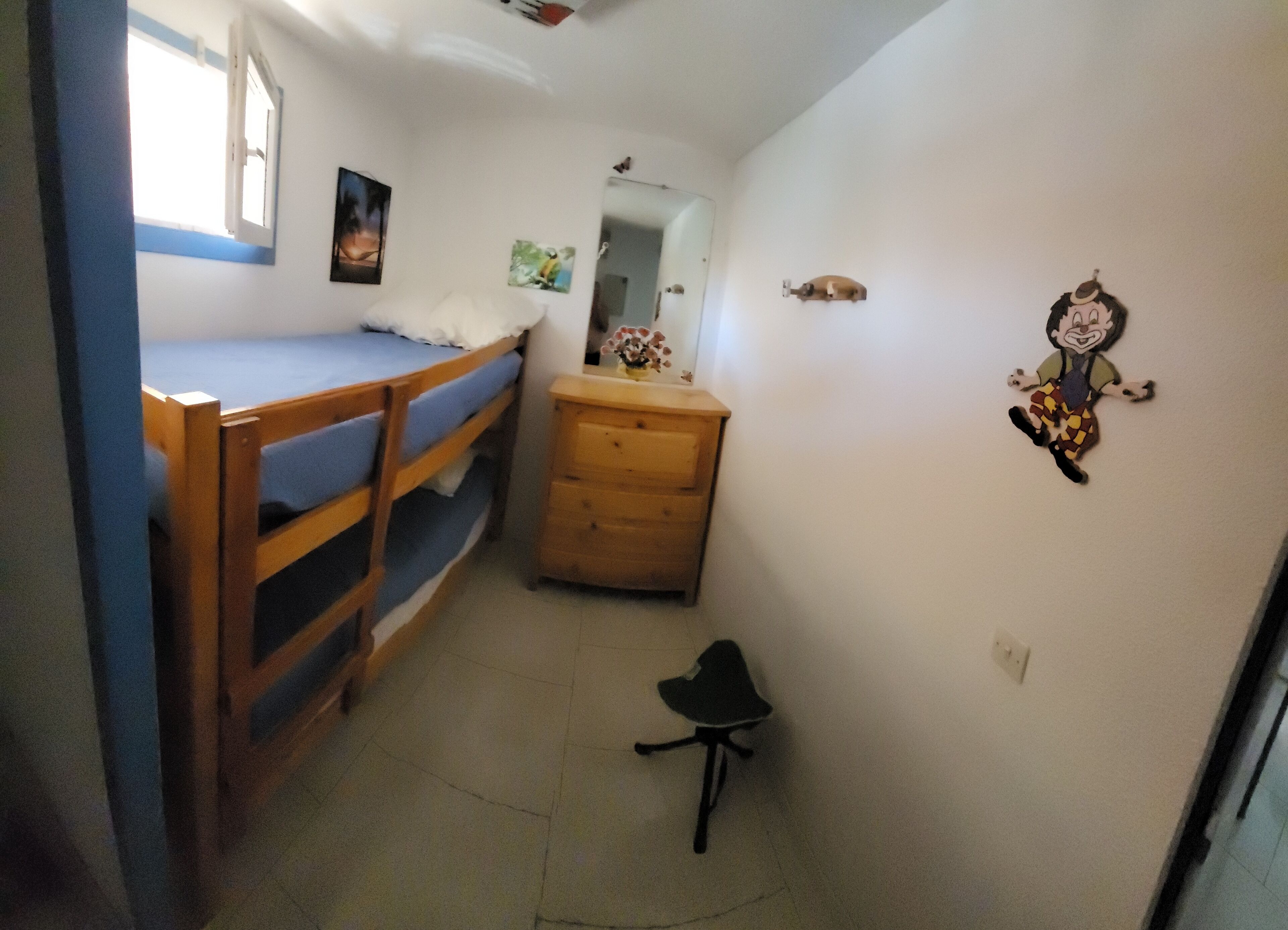 Una camera del dormitorio con letti a castello, una cassettiera, una sedia e uno specchio.