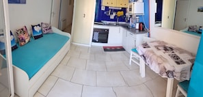 Une pièce de taille modeste comprenant un lit, une petite table, un coin cuisine et une salle de bain.