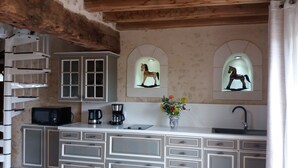 Une cuisine dotée d’un îlot central, de meubles blancs, d’un four à micro-ondes, d’une machine à café et d’un vase rempli de fleurs.