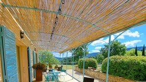 Eine Außenpatio mit Rattanmöbeln, ein überdachter Bereich mit Bambusdecke und Blick auf die Landschaft.