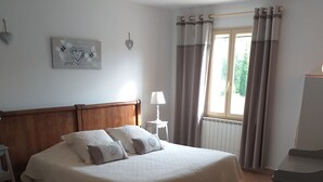 Ein Schlafzimmer mit zwei Betten, einem Nachttisch mit Lampe, einem Schminktisch und einem Fenster mit Vorhängen.