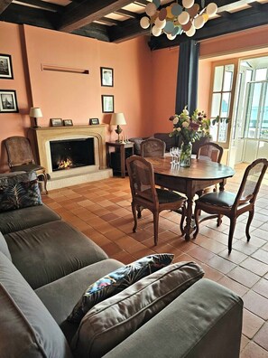 Ein Wohnzimmer mit Kamin, einem Esstisch mit Stühlen und einem Sofa mit Kissen.