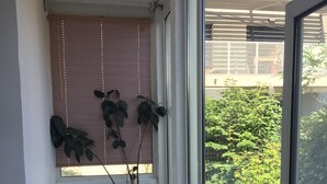Een klein balkon met een bloempot, een witte wasbak en een houten bankje.