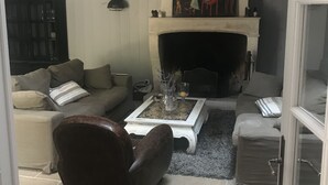 Una sala de estar con chimenea, un sofá, una mesa de centro y un sillón de cuero.