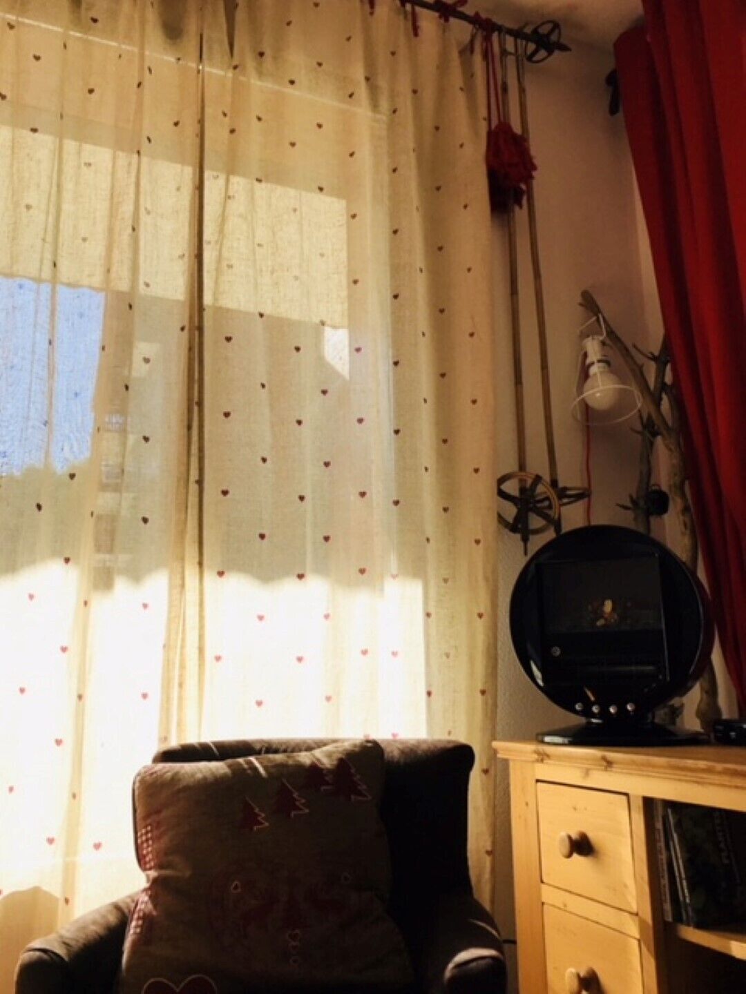A room with a wooden cabinet, a vintage radio, and a chair with a patterned cushion.