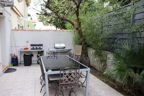 A patio with a table and chairs, a grill, and a trash bin. - Villa F6 10 minutes from the beach, frontignan plage (Frontignan)