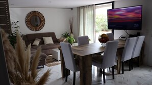 Una sala moderna con comedor, televisor grande y sofá.
