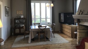 A dining area with a table, chairs, a chandelier, a television, and a fireplace. - House in Yport - 6 people - Near Sea - Between Fécamp and Etretat (Yport)