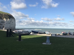 A coastal scene with boats docked near a cliff and the sea.