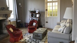 A cozy living room with a checkered floor, a white sofa, two red armchairs, a bookshelf, and a door with a window. - House in Yport - 6 people - Near Sea - Between Fécamp and Etretat (Yport)