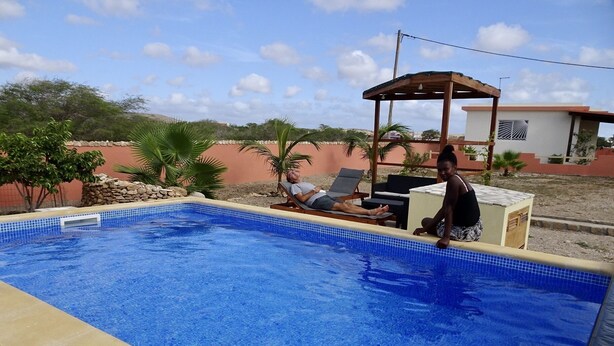 A swimming pool with tiled edges, a wooden pergola, and lounge chairs. - Accommodation for 2 people, swimming pool, bikes in Morro île de Maio (Morro)