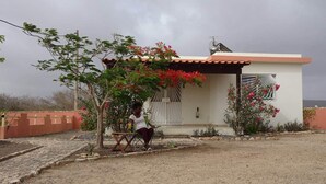 A small house with a tiled roof, a white exterior, and a window with a decorative grille. - Accommodation for 2 people, swimming pool, bikes in Morro île de Maio (Morro)