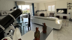 A modern living room with a white sofa, a dining area with a glass table, and a telescope on a stand. - FACING SOUTH SEA VIEW (Carqueiranne)