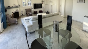 A modern living room with a glass dining table, white sofas, and a fireplace. - FACING SOUTH SEA VIEW (Carqueiranne)