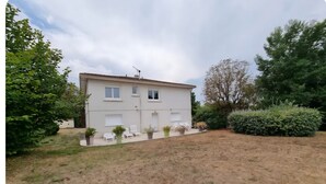 A two-story house with a white exterior, a small front yard, and a large bush to the right. - Country house with wonderful view over the Lot valley (Galapian)