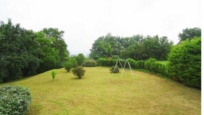 A grassy outdoor area with a swing set and dense trees in the background. - Country house with wonderful view over the Lot valley (Galapian)