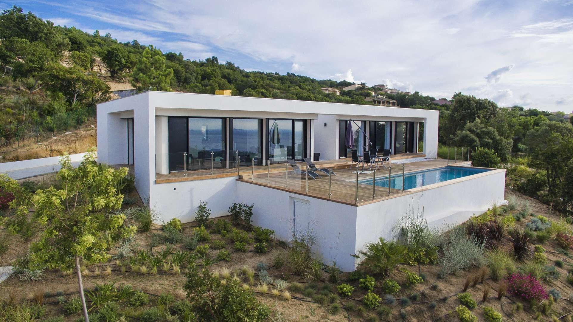A modern house with a large deck and a swimming pool.