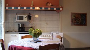 A kitchen with a microwave, stove, and sink. There is a table with a checkered tablecloth and chairs. - House with garden not overlooked in Bergerac quiet (Bergerac)