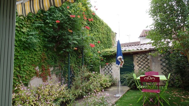 A garden with a patio area, a table with chairs, and a blue flag. - House with garden not overlooked in Bergerac quiet (Bergerac)
