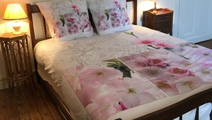 A bed with floral bedding, two bedside lamps, a wooden nightstand, and a white door. - House with garden not overlooked in Bergerac quiet (Bergerac)