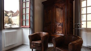 Une pièce comprenant deux fauteuils en cuir, une grande armoire en bois et une vue sur la ville, visible par une fenêtre.