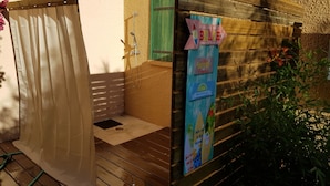 A wooden deck with a shower area, a green door, and a signboard with holiday-themed graphics. - Very nice little villa at the Franqui  (Leucate)