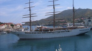 A large white cruise ship docked at a port with a mountainous backdrop and a town with red-roofed buildings. - Stunning fully renovated apartment with air-conditioning  (Pyrénées-Orientales)