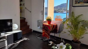 A modern room with a TV, a dining table with a colorful tablecloth, a chair, and a potted plant. - Stunning fully renovated apartment with air-conditioning  (Pyrénées-Orientales)