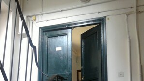 Una escala que mena a una porta verda foscament, amb un petit finestral a la part superior.