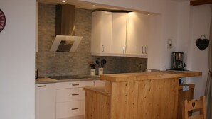 A modern kitchen with white cabinets, a wooden island, and a coffee maker. - Chalet Jonquille - 12 persons with outdoor Jacuzzi, 6 bedrooms (Oz)