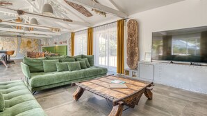 Uma sala de estar moderna com um sofá verde, uma mesa de centro de madeira e uma televisão grande.