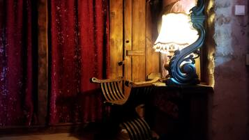 A room with a wooden door, a lamp on a table, and a patterned rug on the floor.