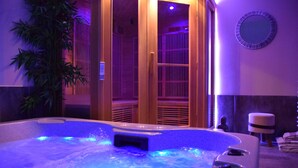 A hot tub with blue lighting, a wooden door, and a mirror on the wall.